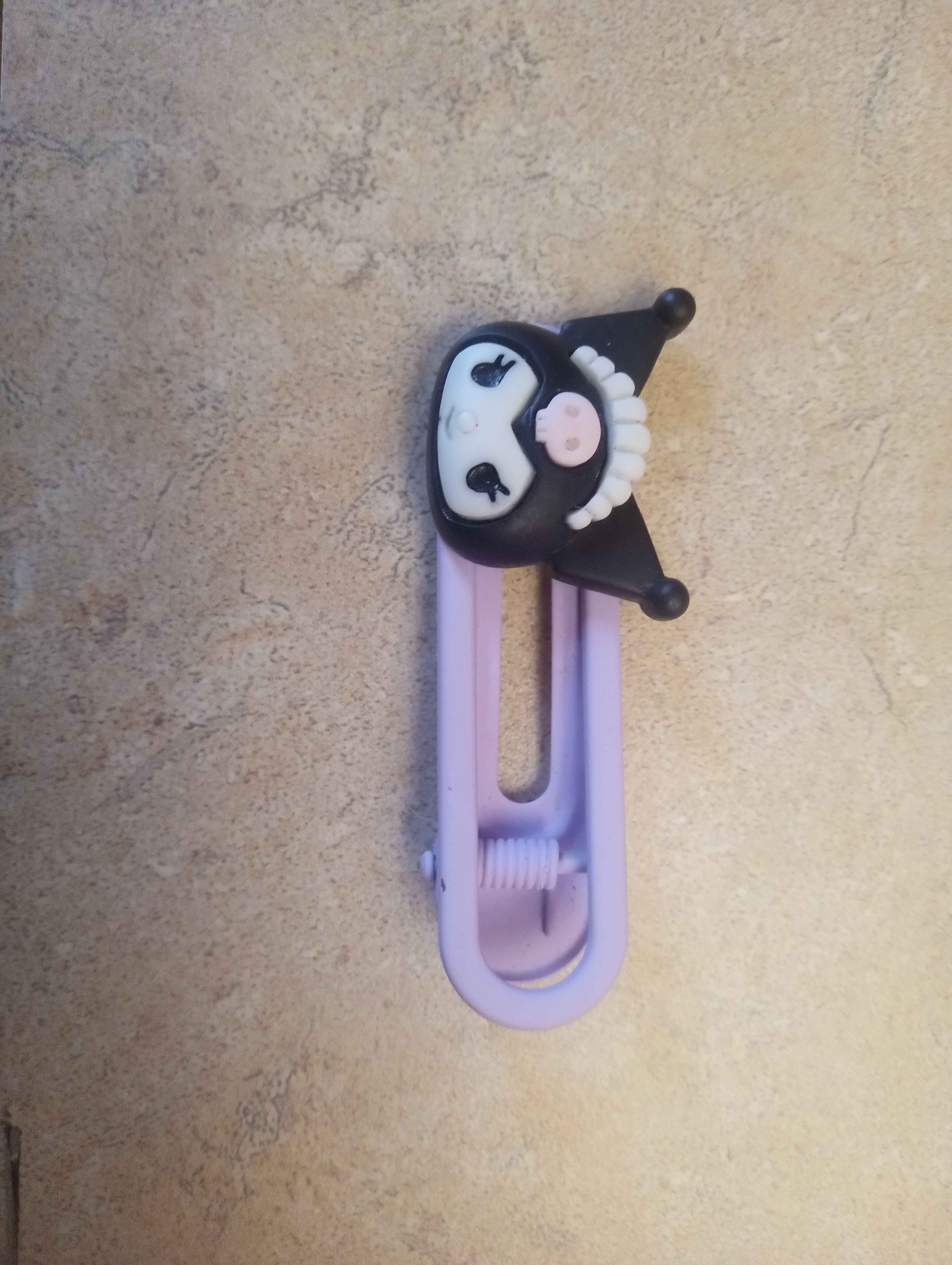 a purple hairclip with kuromis head on one end she's wearing a little maid headpiece